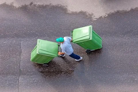 Garbage man at work moving trash containers, top view Stock-Fotos