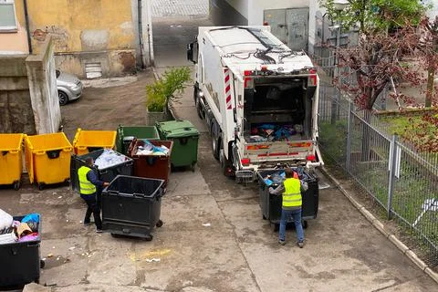 Garbage man working together on emptying dustbins for trash removal. Stock Photos