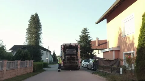 Garbage men collecting trash bins and loading them into the garbage truck. Stock Footage 134880724