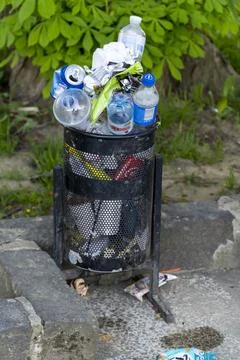Garbage piles, and overflows the trash cans on city Stock Photos