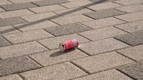 Garbage pollution - a coca cola can left as a trash on city sidewalk rolls over  Stock Footage 170557971