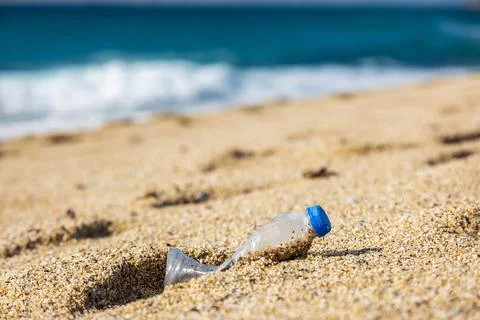 Garbage pollution of the planet. Empty plastic bottle on the beach sand Stock Photos