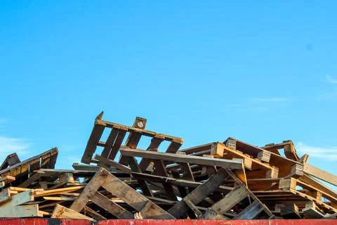 Garbage removal. A large pile of used wooden pallets lies in a metal trash Stock Photos
