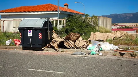 Garbage scattered on the street next to the garbage container. Video stock 246314599