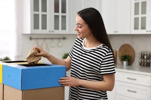 Garbage sorting. Smiling woman throwing crumpled paper into cardboard box i.. Stock Photos