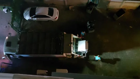 Garbage truck and workers cleaning up trash on street in evening, top view Vídeo Stock 303620876