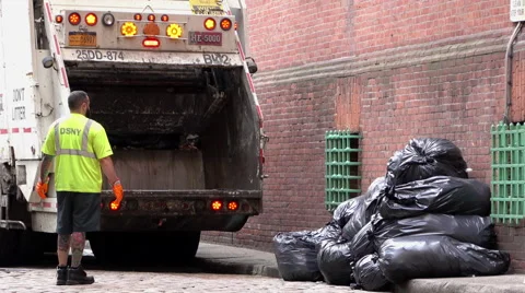 Garbage truck backs up to stacks of trash bags in NYC 4k Video stock 68207191