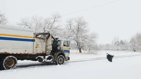 Garbage truck dumps garbage can in snow storm Stock Footage 70084525