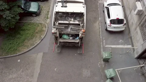 Garbage truck idling, worker rolls three bins to truck. Video stock 132506705