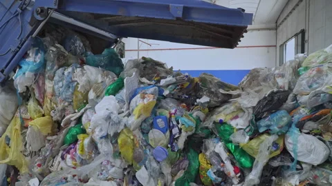 A garbage truck unloading plastic waste inside a recycling center Stock Footage 263611994