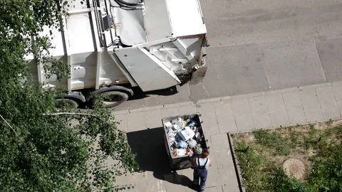 Garbage truck. Worker removes garbage from the container near the house Stock Footage 78575196