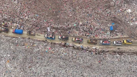 Garbage trucks driving through a massive landfill in bali Stock Footage 327813409