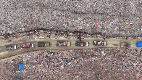 Garbage trucks queueing at a huge landfill in bali Stock Footage 327813402