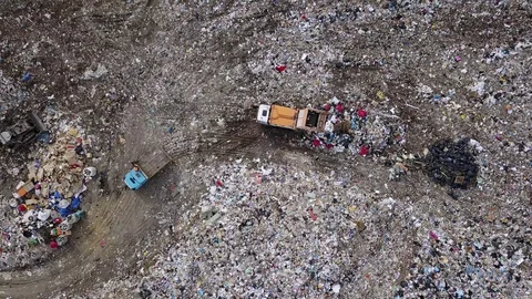 Garbage trucks unload garbage to a landfill in the vicinity of the city of Stock-Footage 89542287