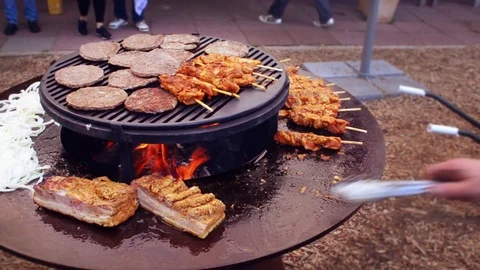 Garden barbecue adding Livar pork roast to the hot plate Stock Footage