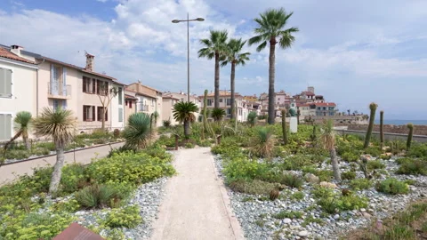 A garden with cacti, palm trees and gravel paths overlooking old town Antibes Stockbeeldmateriaal 344816466