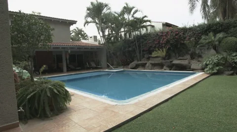 A garden fitted with a big pool and tropical trees Video stock 48787845