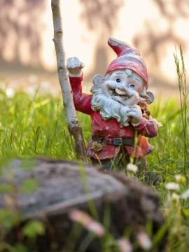 Garden gnome is leaning against a tree Stock Photos