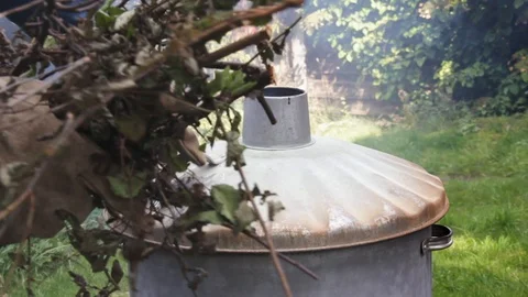 Garden incinerator, man adding garden waste to smokey incinerator Stock Footage 87177616