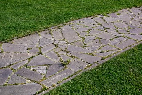 Garden path made of natural stone paved with different size rough rock. Stock Photos