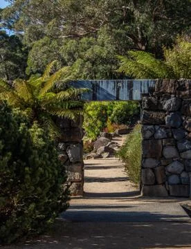 Garden path,  rock feature wall, arch doorway, stone walkway surrounded by trees Stock Photos