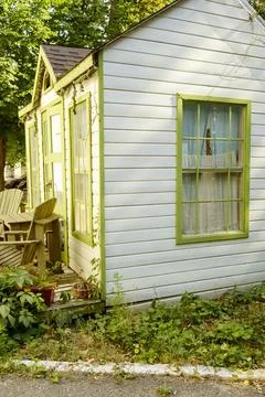 Garden scene with a rustic timber cottage and vibrant vegetation in summer. Stock Photos