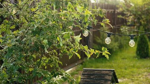 Garden string lights hanging during summer rain Stock Photos