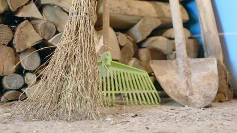 Garden tools like tree branches broom, rake and shovel in storage building near Stock Footage 260825898