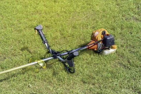 Garden trimer with a gasoline engine on the background of summer grass. Stock Photos