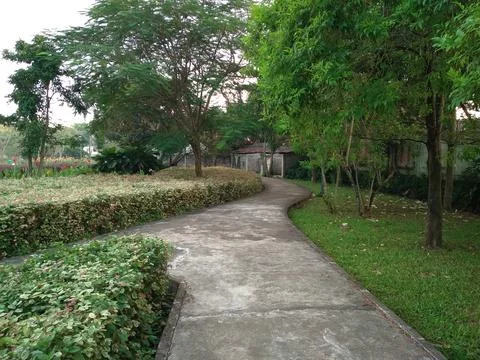 Garden view with a concrete path winding through Stock Photos