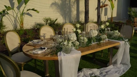 Garden wedding table with white flowers gold chairs and flowing runner Stock Footage 344512233