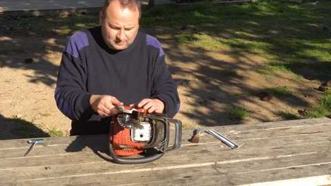 Garden worker doing the maintenance of a chainsaw Stock Footage 107054838