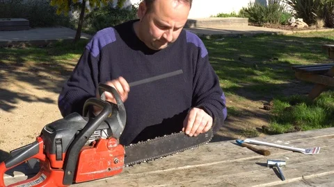 Garden worker doing the maintenance of a chainsaw Stock Footage 107054893