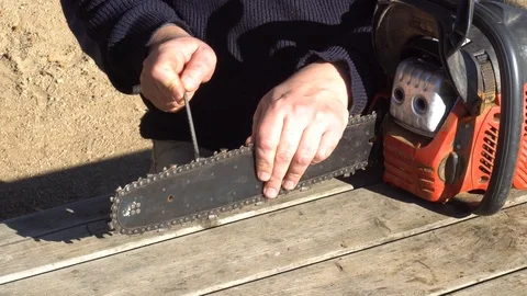 Garden worker doing the maintenance of a chainsaw Stock Footage 107054972