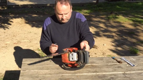Garden worker doing the maintenance of a chainsaw Stock Footage 107054974