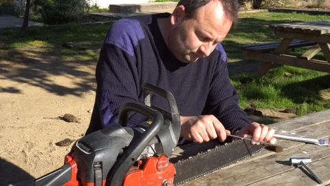 Garden worker doing the maintenance of a chainsaw Stock Footage 107055192