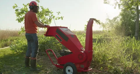 Garden worker using wood chipper shredder machine for making mulch Stock Footage 297944399