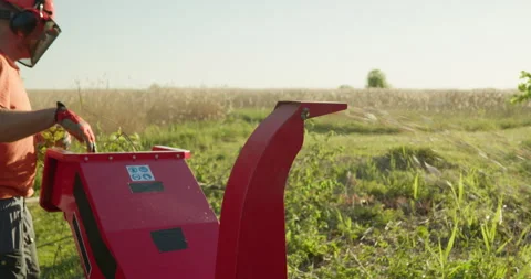 Garden worker using wood chipper shredder machine to make branch mulch Stock Footage 306278897