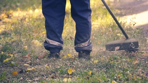 Gardener cutting grass with a hand-held lawnmower in slow motion Stock Footage