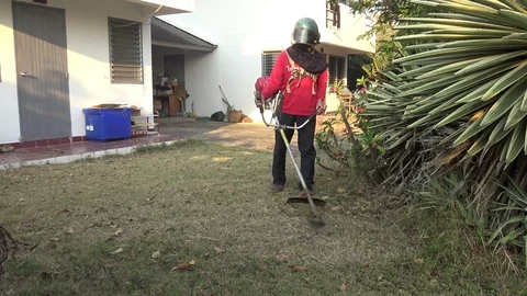 Gardener cutting  grass with lawn string trimmer in front of the house. 스톡 동영상 88234645