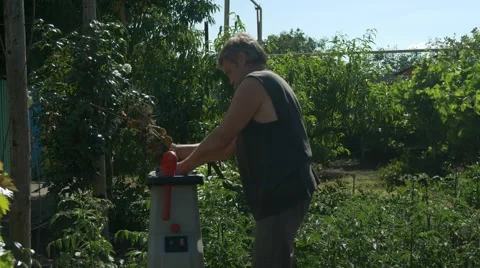 The gardener does mulch using branches shredder. Production of sawdust Stock Footage 65886192