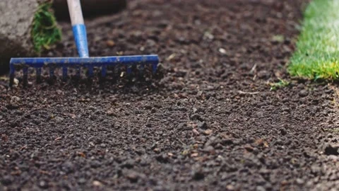Gardener Grading Out Soil With A Rake. SLOW MOTION. Planting green grass lawn. Vidéo 140369247