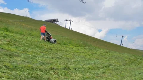 Gardener maintaining grass on mountain ski slope during summer Stock Footage 283305461
