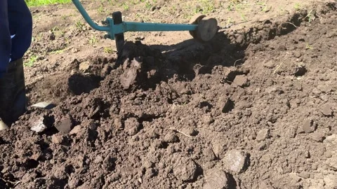 Gardener in spring plow ground soil with electric cultivator Stock Footage 277623522