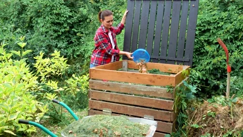 Gardener throwing out kitchen waste to the garden compost heap for recycling Stock Footage 220505812