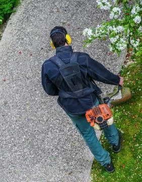 Gardener using corded string trimmer in a park Stock Photos