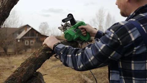 Gardener using electric circular saw makes cut on old apple tree trunk Stock Footage 256252227