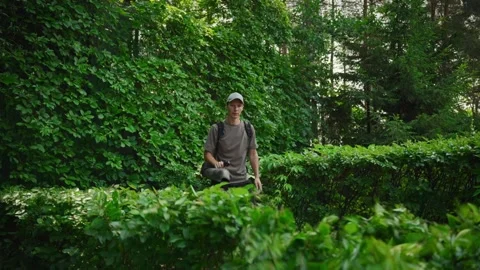 Gardener using professional leaf blower to clear foliage from shrubs and plants Stock Footage 316287919