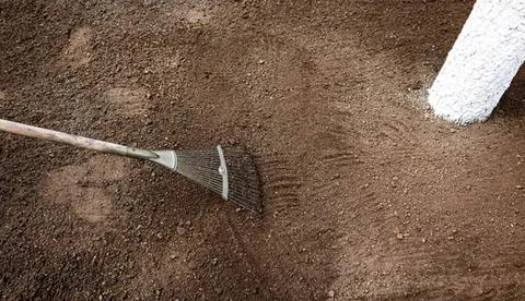 Gardener using rake to loosen soil in garden bed Stock Photos