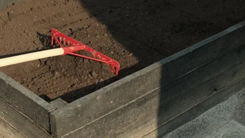 Gardening preparation with a rake leveling soil in a raised bed Stock Footage 331474669